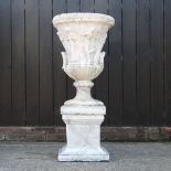 A weathered reconstituted stone faux marble garden urn, on a pedestal base,