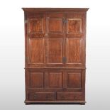 An 18th/19th century oak cabinet, enclosed by a pair of panelled doors, with drawers below,