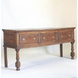 An 18th century oak dresser base, containing three short drawers, on turned legs,