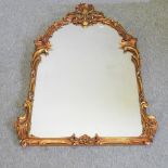 An ornate gilt framed wall mirror, with an arched top,