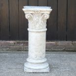 A marbled reconstituted stone garden pedestal, in the form of a corinthian column,