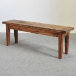 A rustic pine bench, on square legs,