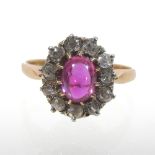 An unmarked ruby and diamond cluster ring, of flower head design, with a central cabochon ruby,