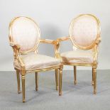 A pair of French style gilt and cream upholstered armchairs