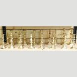 A collection of pairs and single turned brass candlesticks,