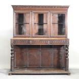 A 19th century carved oak cabinet on stand, with a glazed upper section, on turned supports,