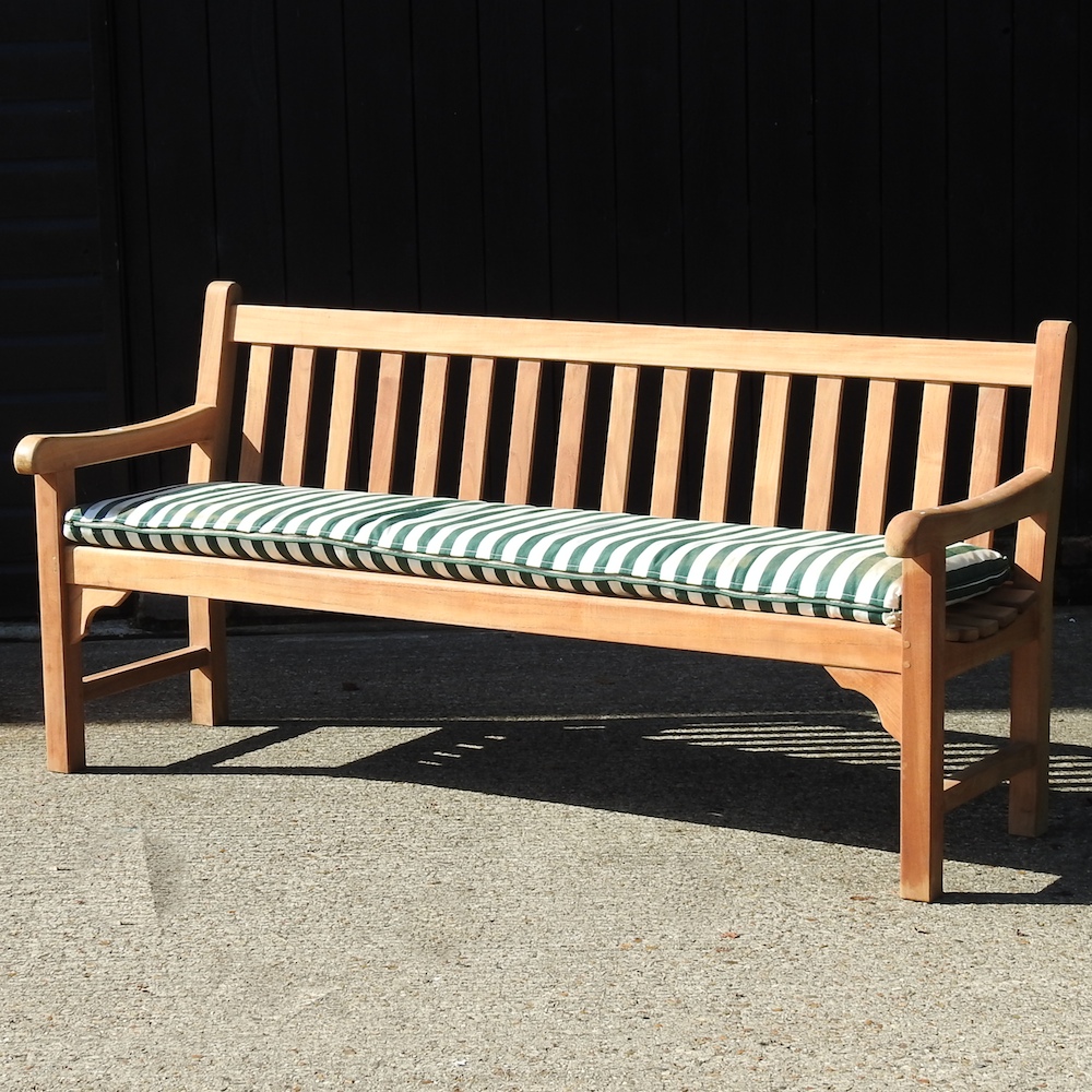 A teak slatted garden bench, with a loose cushion,