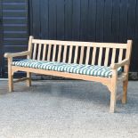 A teak slatted garden bench, with a loose cushion,