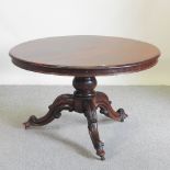 A Victorian rosewood circular dining table, on a carved tripod base,