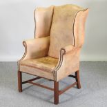 A brown leather upholstered and studded wing armchair