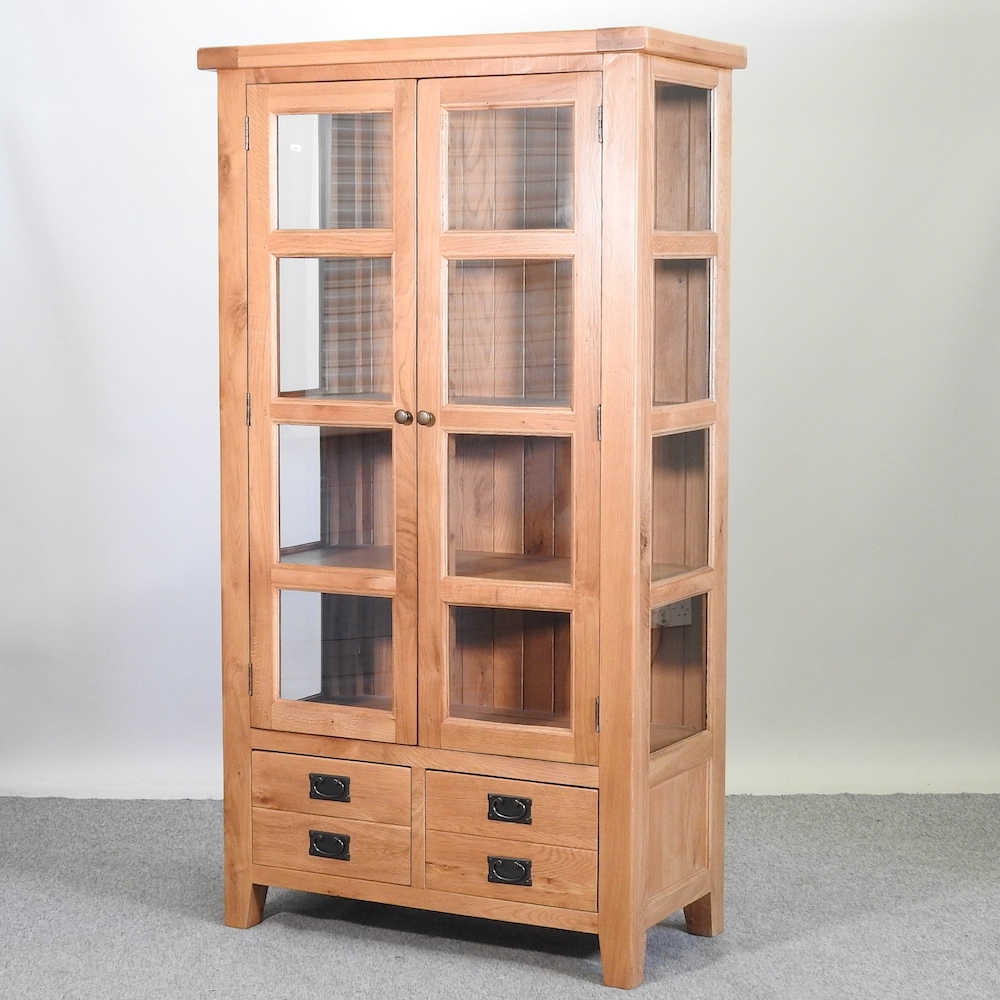 A modern glazed light oak cabinet,