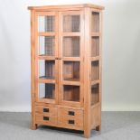 A modern glazed light oak cabinet,