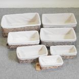 A set of seven graduated wicker baskets, with fabric liners,