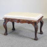 A striped upholstered footstool, on claw and ball feet,