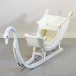 A cream painted wooden sleigh, in the form of a swan,