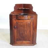 A Victorian mahogany corner washstand, containing a single door,