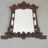 A large and ornate Eastern carved hardwood framed wall mirror,