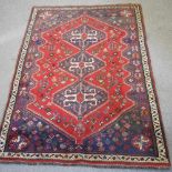 A Turkish woollen rug, with geometric design, on a red ground,