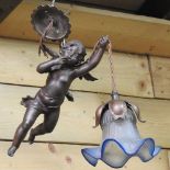 A late 19th century bronzed hanging ceiling light, in the form of a cherub, with a glass shade,
