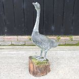 A life size metal garden model of a goose, on a wooden base,