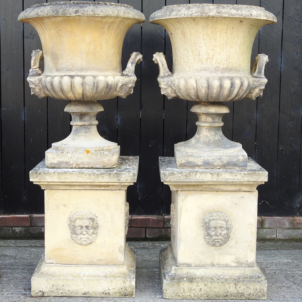 A pair of large reconstituted stone garden urns, each of campana shape,