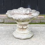 A reconstituted stone bird bath, in the form of a shell,