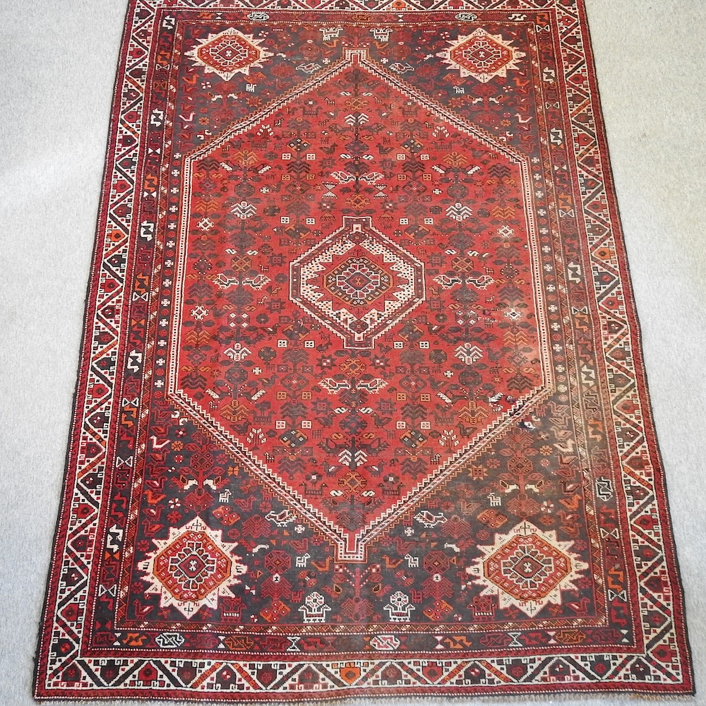 A Persian woollen rug, with geometric design, on a red ground,