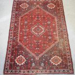 A Persian woollen rug, with geometric design, on a red ground,