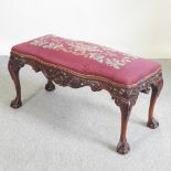 A carved serpentine footstool, with a tapestry seat,