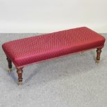 A Victorian style red upholstered mahogany footstool, on turned legs and ceramic castors,