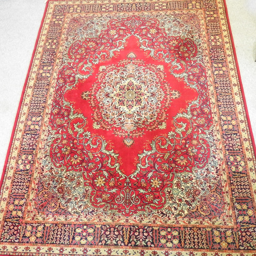 A Persian woollen carpet, with foliate design, on a red ground,