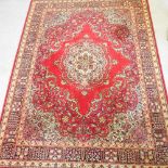 A Persian woollen carpet, with foliate design, on a red ground,