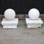 A pair of sandstone gatepost finials, each of ball shape, on a plinth base,
