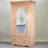 An antique pine single wardrobe, with a mirrored door, and a drawer below,