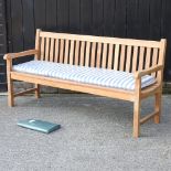 A teak slatted garden bench, with a loose cushion and cover,