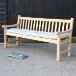 A teak slatted garden bench, with a loose cushion and cover,