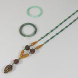 An oriental jade coloured hardstone bangle, together with another and an Eastern bead necklace,