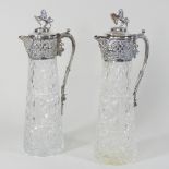 A pair of early 20th century cut glass and silver plated claret jugs, each surmounted with a lion,