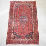 A Persian woollen rug, with geometric design, on a red ground,