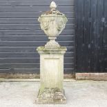 A large reconstituted stone garden urn and cover, on a pedestal base,