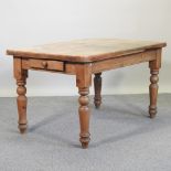 An antique pine kitchen table, with a single drawer, on turned legs,