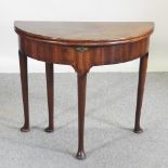 A George III mahogany fold-over tea table, on turned legs,