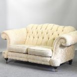 A cream upholstered chesterfield sofa,