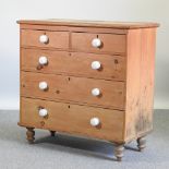 A 19th century stripped pine chest of drawers, with white pottery handles, on turned feet,