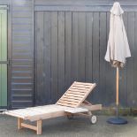 A teak garden lounger, with a drinks tray, and a loose cushion,