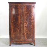 A mid 20th century bow front double wardrobe, on bracket feet,