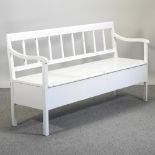 A white painted open back settle, with a hinged seat,