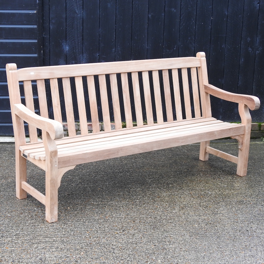 A teak slatted garden bench, with a loose cushion,