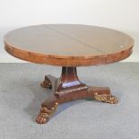 A 20th century extending circular centre table, of Regency style, on gilt paw feet,