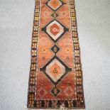 An early 20th century Persian woollen runner, with three central lozenges and geometric designs,